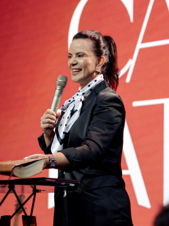 Pastora Camile Fatuch sorrindo com o microfone no palco do Beleza que Cura