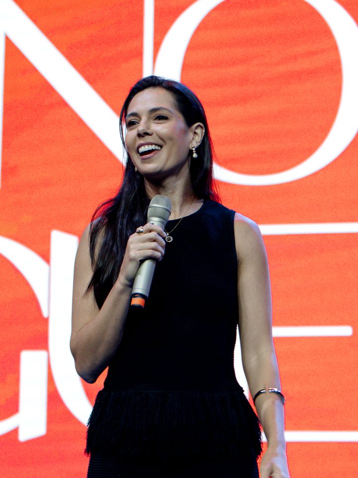 Dra. Manoela Guedes Correa sorrindo com o microfone no palco do Beleza que Cura