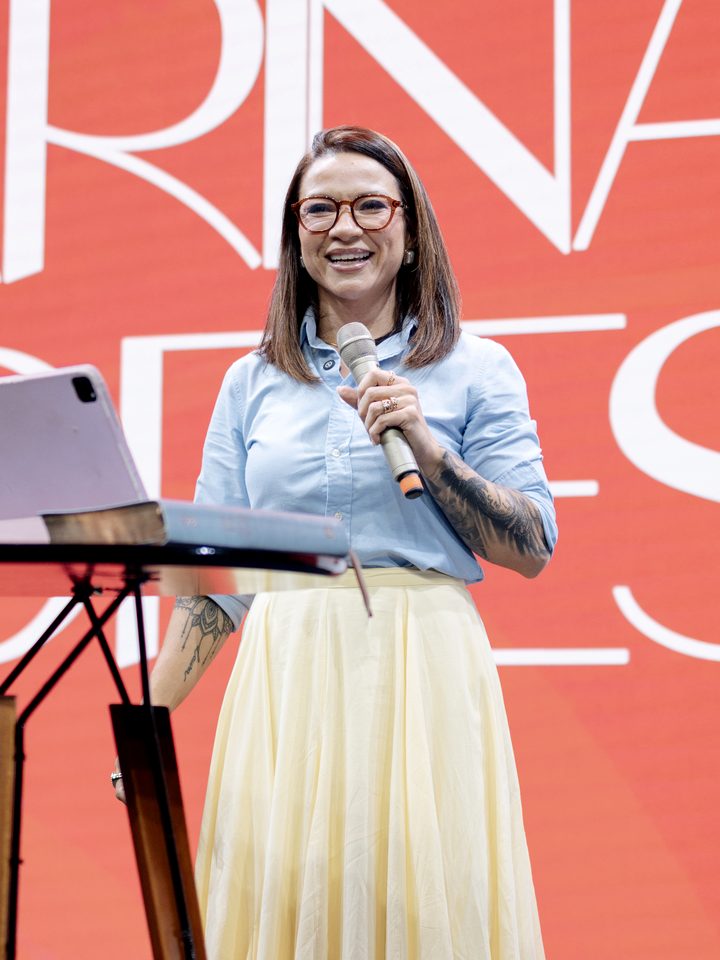 Karina Lopes sorrindo com o microfone no palco do Beleza que Cura